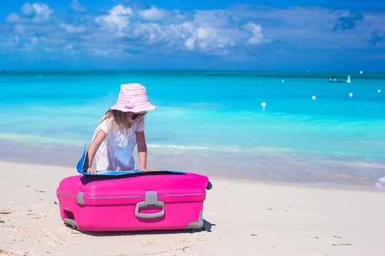 Little adorable girl with big colorful suitcase and a map on