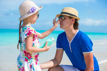 Little girl gets sun cream on her dad's nose