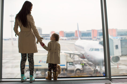 Mother and little daughter looking out the window at airport