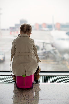 Little girl looking out the window at airport terminal