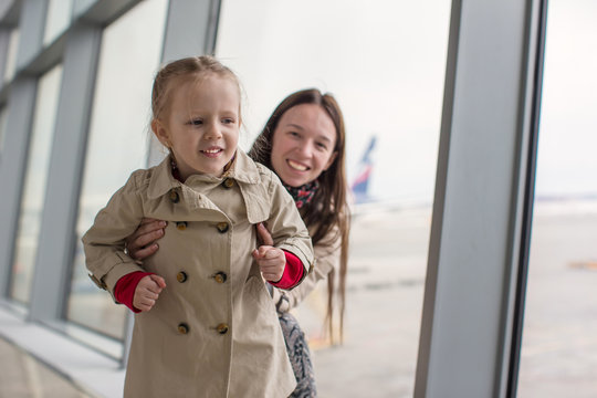 Mother and little daughter near the window at airport terminal