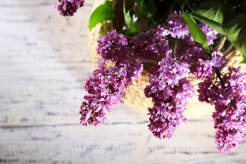 Beautiful lilac flowers in vase, on color wooden background