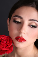 Fototapeta na wymiar Girl with red lips and rose on dark background