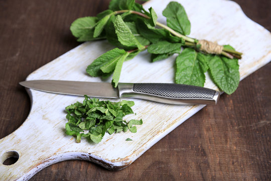 Mint on cutting board, on color wooden background