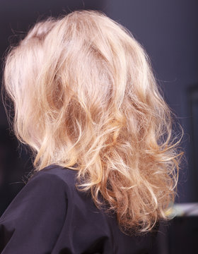 Female blond wavy hair. Back of woman head. Hairdressing salon.