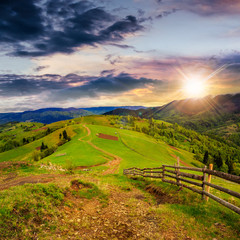 fence on hillside meadow in mountain at sunset