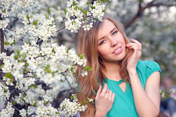 Beautiful blonde girl on the background of white flowers
