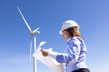 Female engineer holding a blueprints at wind farm