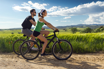 Obraz premium Happy young couple on a bike ride in the countryside