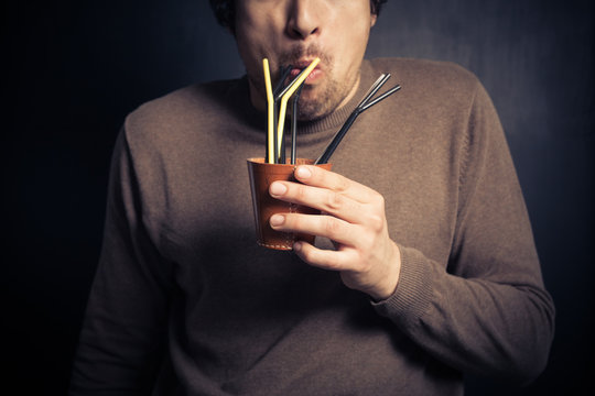 Silly young man drinking from leather cup with straws