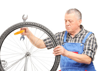 Mature bicycle mechanic looking at a wheel