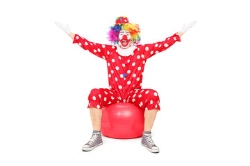 Overjoyed clown sitting on a fitness ball
