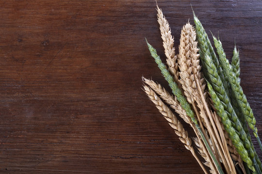 green and ripe wheat on a wooden background