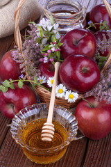 apples in a basket with honey and flowers on wooden table