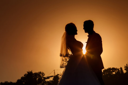 silhouette of a young bride and groom on Sunset background