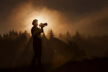 silhouette of woman photographer taking photos in forest with fo