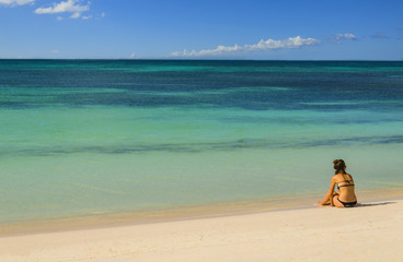 Fototapeta na wymiar Młoda kobieta siedzi samotnie na plaży