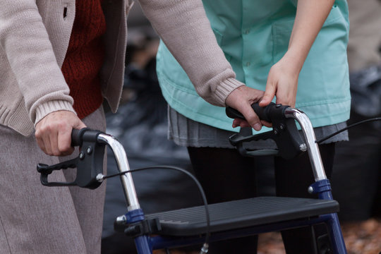 Nurse helping disabled lady with walker