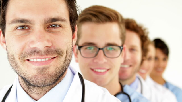 Team of doctors standing in row smiling at camera