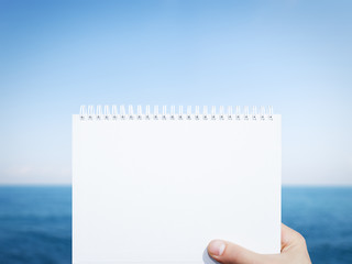 horizontal white blank notebook in man hand with sea background