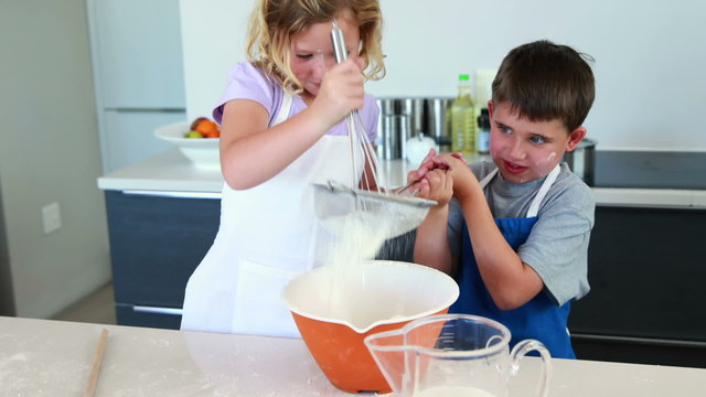 Smiling siblings making a cake together