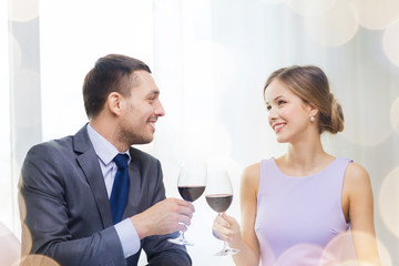 young couple with glasses of wine at restaurant