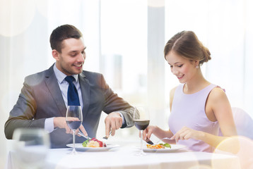 smiling couple eating main course at restaurant