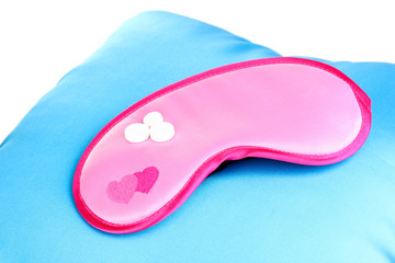 Sleeping mask and tablets on pillow isolated on white