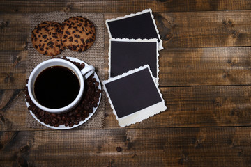 Coffee cup, cookies and old blank photos, on wooden background