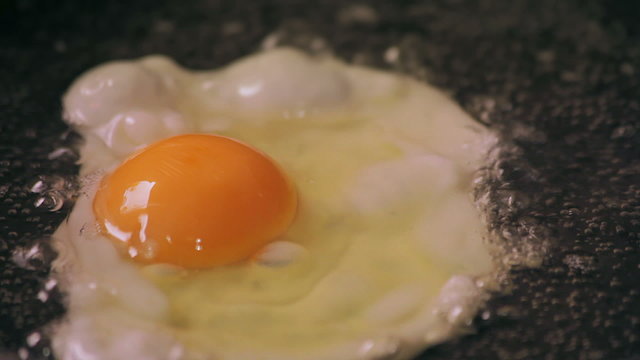 Egg cooks on frying pan