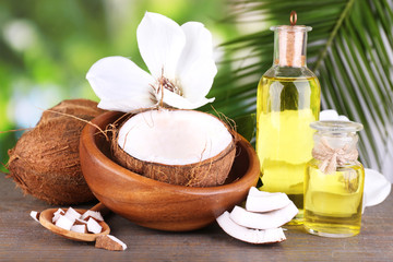 Coconuts and coconut oil on wooden table, on nature background © Africa Studio