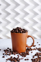 Cup full of coffee beans on light background