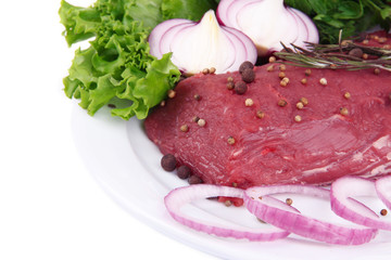 Raw beef meat with vegetables on plate close up
