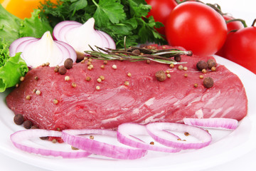 Raw beef meat with vegetables on plate close up