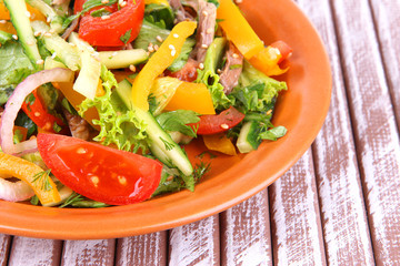 Beef salad on plate on wooden background