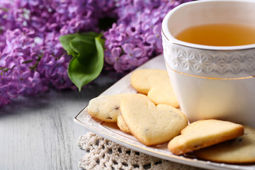 Lavender cookies and cup of tasty tea on color wooden
