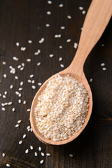 Spice sesame in spoon on wooden background