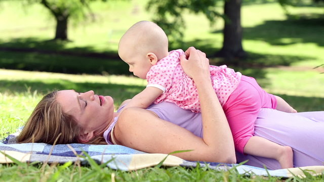 Happy mother playing with her baby girl in the park