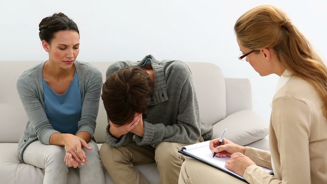 Young unhappy couple talking with their therapist