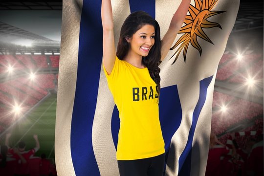 Excited football fan in brasil tshirt holding uruguay flag