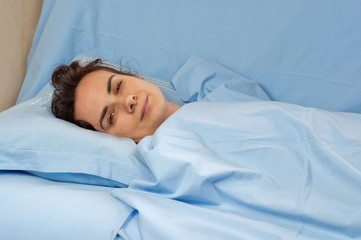 Young woman lying sick in bed