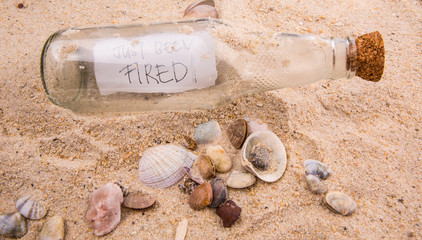 Concept image of a message JUST BEEN FIRED in a bottle