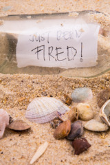 Concept image of a message JUST BEEN FIRED in a bottle