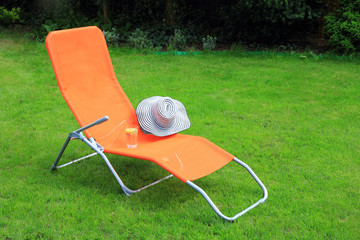orange lounge sunbed standing on green grass - 64712088