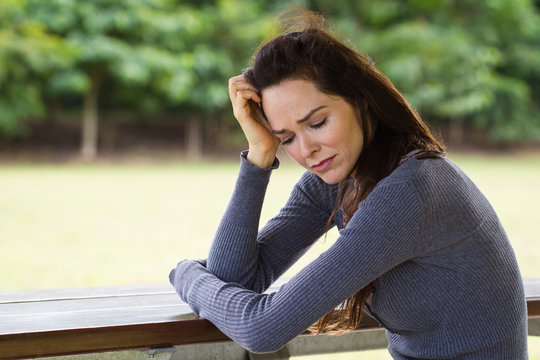Sad and upset woman sitting outdoors