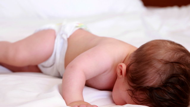 Baby in diaper crawling on bed