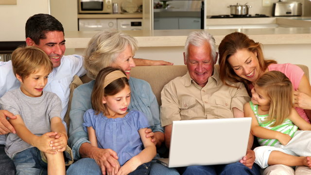 Extended family using laptop together on couch