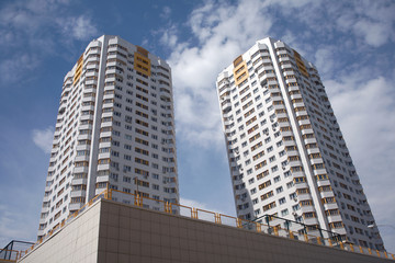 Fototapeta na wymiar Two residential buildings in a city over blue sky with clouds