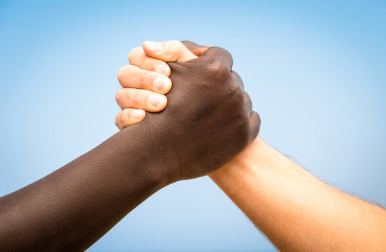 Black and white human hands shake - Handshake against racism