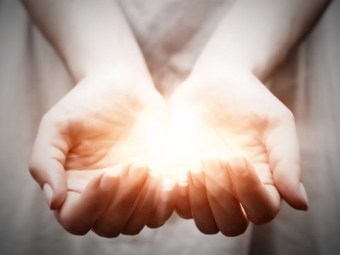 The light in young woman hands. Sharing, giving, protection